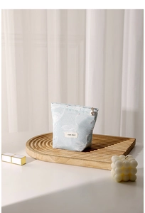 Detail view of light blue swan jacquard makeup bag with branded label and zipper closure