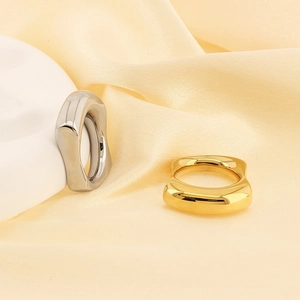 Detailed shot of irregular 18k gold and silver rings on elegant yellow satin fabric