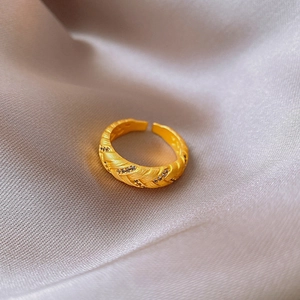 Detail of matte gold oval ring featuring woven texture and small inlaid zircons