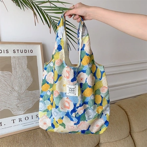 Borsa tote floreale in tessuto stropicciato tenuta da modella in ambiente moderno