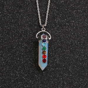 Hexagonal white crystal pendant with seven colorful chakra stones on a black texture