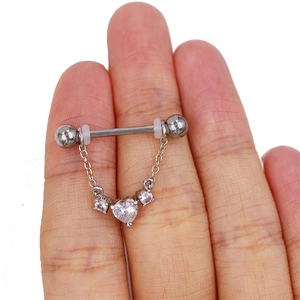 Nahaufnahme von silbernem Brustpiercing mit herzförmigem Zirkonia und feiner Metallkette
