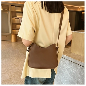 Détail d'un sac bandoulière marron en similicuir avec bandoulière réglable et texture