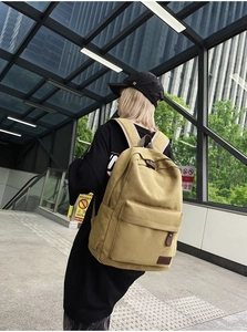 Close-up of khaki canvas backpack featuring durable leather pullers and external pockets