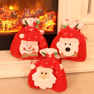 Three Christmas drawstring gift bags featuring Santa, snowman, and bear by a fireplace