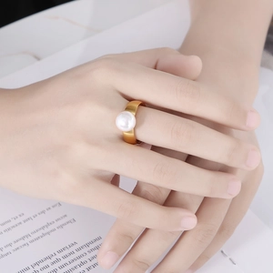 Detail of a brushed gold stainless steel ring featuring a single lustrous white pearl
