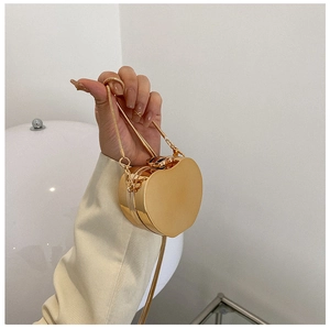 Detail of a heart-shaped gold metallic evening clutch with a polished mirror finish and chain