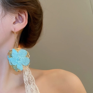 Gros plan détaillé de boucles d'oreilles fleurs bleues avec dentelle métallique dorée