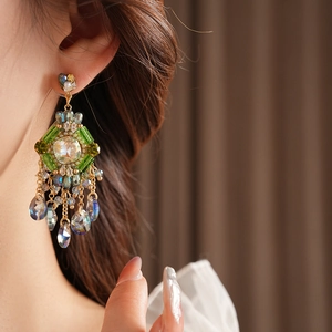 Detail shot of bohemian gold tassel earring with green gems and crystal teardrops