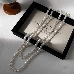 Detail showing long multi-layer white pearl necklace with high-luster beads on a display box