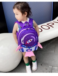 Toddler purple rocket backpack with star patterns and safety leash shown on girl