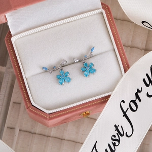 Detailed close-up of blue zircon flower earrings set in a premium pink velvet jewelry box