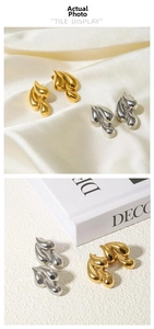 Close-up of teardrop stud earrings in gold and silver finish on elegant white satin