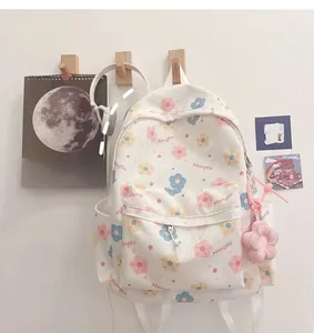 Detail of cream backpack with floral prints and cute pink plush flower pendant on a hook