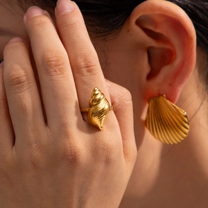 Macro shot of gold seashell ring and shell earring with realistic ocean textures