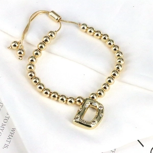 Macro view of gold beaded bracelet featuring a sparkling zircon initial D pendant detail