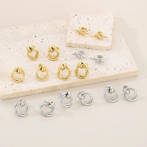 Macro detail of intertwined gold and silver twisted knot stud earrings on stone