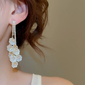 Gros plan de boucles d'oreilles élégantes à fleurs plaquées or 18k portées par un modèle