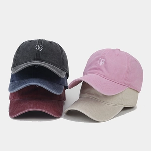 Detail view of five washed cotton baseball hats with small heart embroidery in various colors