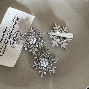 Detail of silver snowflake hair clips with pearls and rhinestones on a ceramic plate