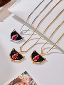 Vue macro des pendentifs en éventail doré et argenté avec perle rouge sur chaînes serpent