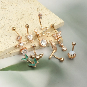 Macro shot of rose gold belly rings with zircon hearts and butterflies on stone