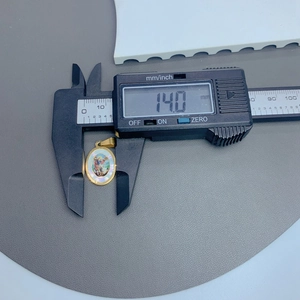 Detailed measurement of stainless steel Guadalupe pendant showing 14.0 mm on digital caliper