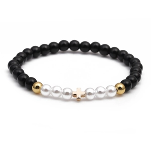 Minimalist beaded bracelet with black beads, white pearls, and a golden cross charm