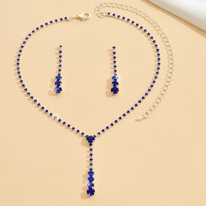 Flat lay of shimmering deep blue crystal necklace and teardrop earrings bridal set