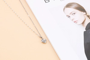Detail of silver heart pendant with sunburst engraving on a minimalist chain necklace