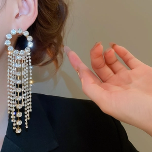 Close-up of sparkling silver tassel earrings with round crystals on model side view