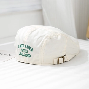 Detail of CATALINA 1983 embroidery and copper buckle on beige cotton beret cap