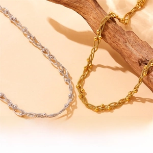 Detail of gold and silver twisted chain necklaces with beads on a wooden branch
