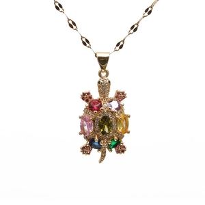 Golden turtle necklace with colorful zircons and gemstones on a crisp white background