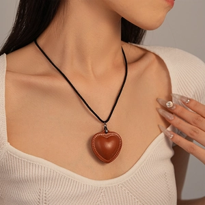 Minimalist long faux leather heart pendant necklace with woven cord on female model