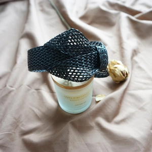 Detail showing a black woven wide knotted headband on a candle in a romantic setting