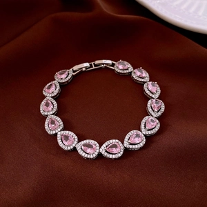 Détail d'un bracelet argenté avec pierres roses en poire sur soie rouge
