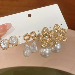 Macro detail of gold floral and heart earrings set with lustrous white pearls