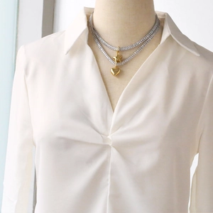 Double-layered gold heart and star pendant necklace on a white shirt model display