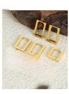 Detail view of rectangular gold titanium earrings in various sizes on a textured background