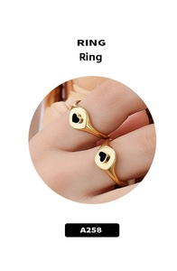 Gros plan d'une bague chevalière plaquée or avec cœur noir portée au doigt