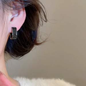 Close-up of black cubic zirconia hoop earring on model with polished metallic finish