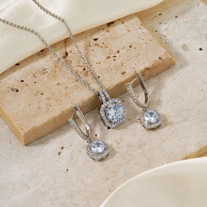 Elegant silver square halo jewelry set with necklace and earrings on silk background