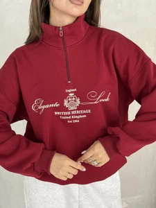 Detail of burgundy half-zip sweatshirt featuring British heritage embroidery and ribbed cuffs