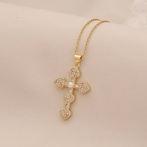 Golden cross necklace with pearl and seashell inlay on elegant beige fabric