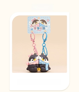 Detail of penguin couple keychains with magnetic embrace and decorative scarves