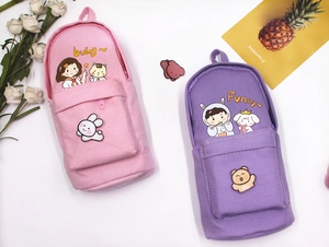 Close-up of cute backpack-shaped canvas pencil cases with cartoon prints and soft patches