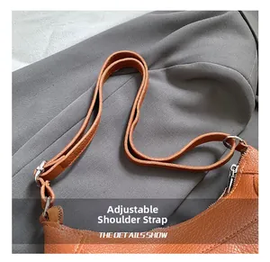 Close-up of adjustable strap and litchi texture on orange leather tote bag