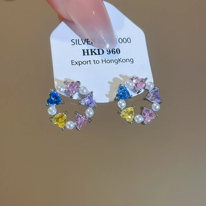Close-up of heart-shaped multi-color gemstone and pearl earrings on a display card