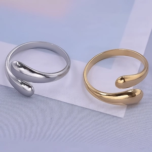 Close-up of minimalist adjustable teardrop rings in polished gold and silver finishes